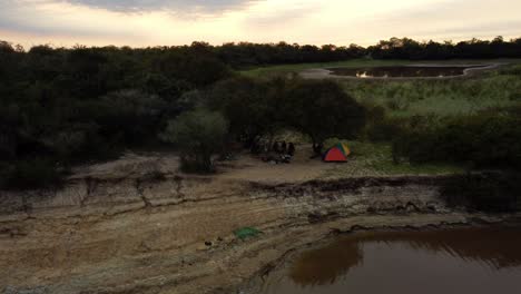 aerial shot at dawn time, group of fishermen camping on tebicuary river side, paraguay