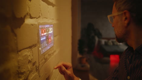 man interacting with a smart home control panel on a brick wall