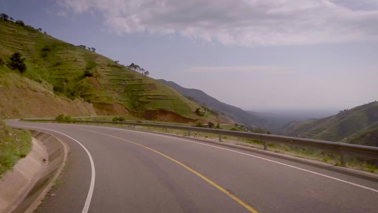 Vista da un veicolo in movimento su strade di montagna tortuose tra bellissime montagne e una valle