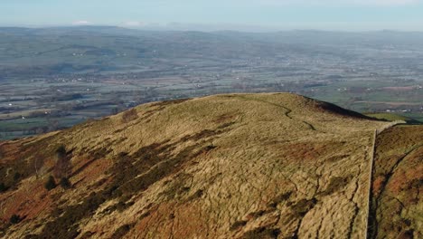 early sunlight on highland mountain peak aerial view across vast frosty idyllic farmland countryside left orbit