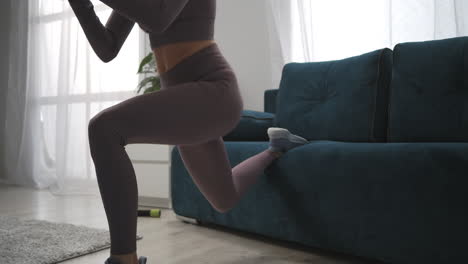 sexy fitness model is training in living room doing squats closeup view on bottom part of female body gym bunny workout at home