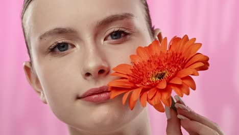 young woman with bright orange flower on vibrant background a serene moment of a woman enjoying the scent of a vibrant orange flower eyes closed in relaxation