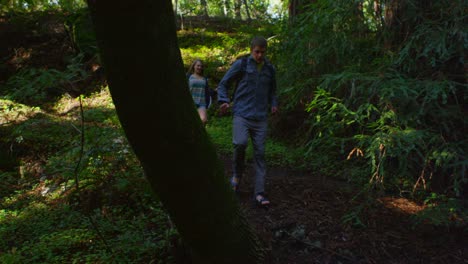 una pareja corre por un camino en un bosque