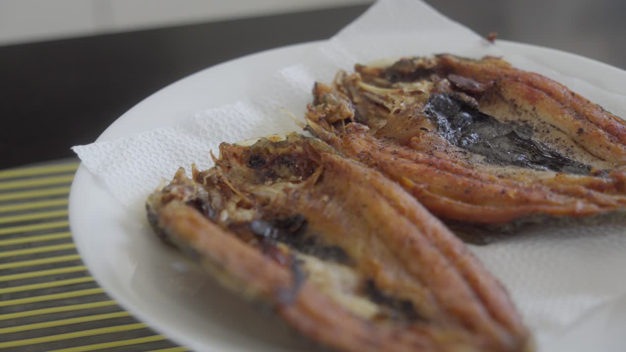Fried Bangus on plate on top of bowl, with tissue paper under, orbit
