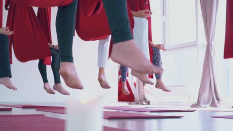 meditating women bare feet hang down from red hammocks