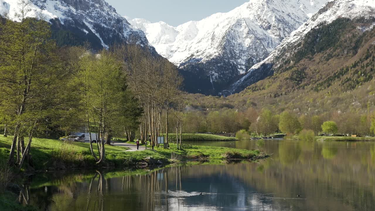 View on the lake of lake Génos-Loudenvielle in the french pyrenees with snow-capped mountains in the background. Ground level point of view.