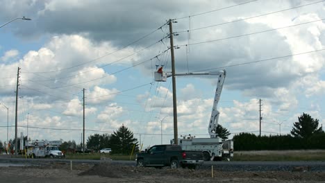 linesman in bucket truck works on overhead electrical wires alone a road