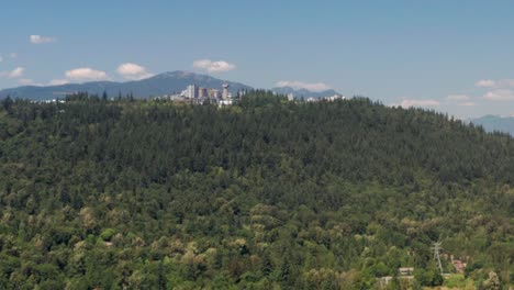 simon fraser university surrounded by lush green forest in the burnaby mountain in canada - aerial shot