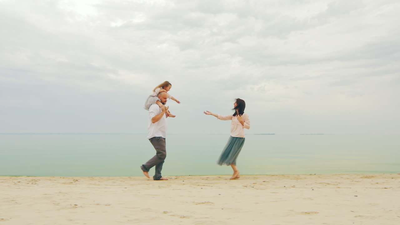 해변에서 달리는 세 사람의 행복한 가족 03