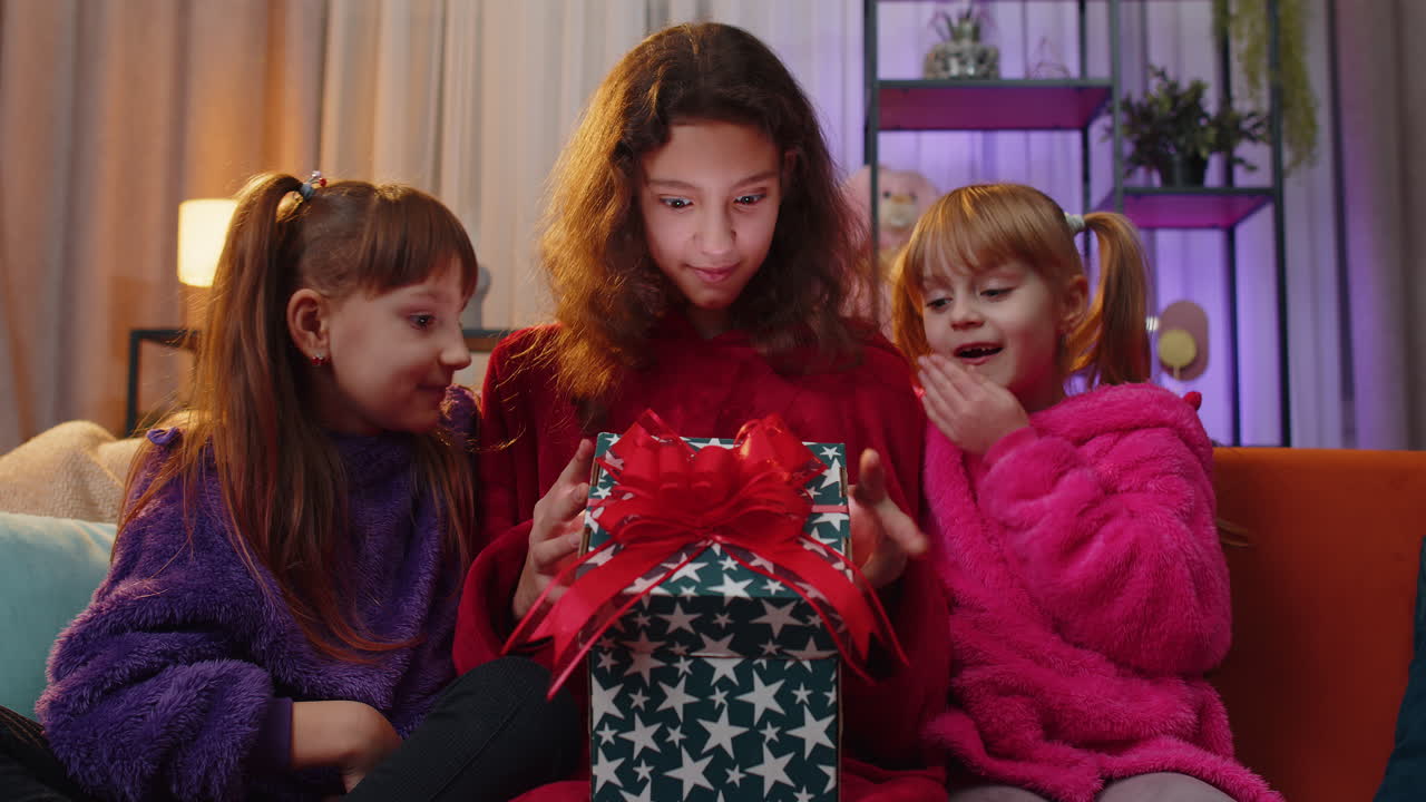 tres hermanos niños niñas abriendo la caja de regalos con emocionada cara sorprendida regalo de cumpleaños brillante