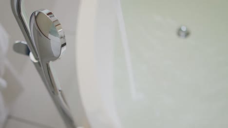 Water-pouring-from-tap-to-bathtub-in-bathroom