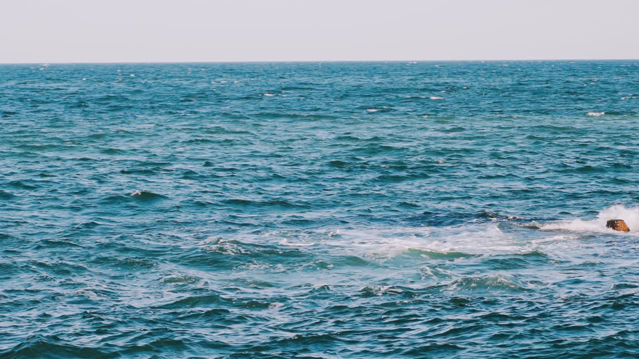 Waves swaying on the sea water. Amazing water background at storm. Beautiful blue water of the ocean with waves and white foam. Slow motion.