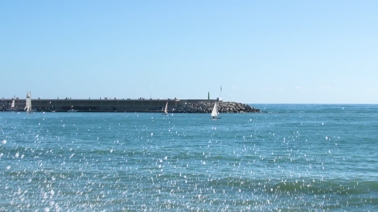 항구 근처에서 항해하는 범선과 부두에서 산책하는 사람들