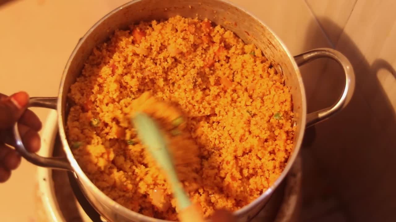 Top down closer view of rice and peas being stirred in a large pot on the stove in slow motion