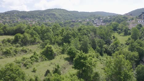 drone flight over green hills and small village
