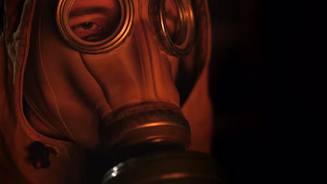 a man in a gas mask looks at the fire the flame is reflected in the mask