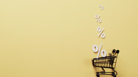 Video-of-shopping-trolley-and-white-percent-signs-on-yellow-background