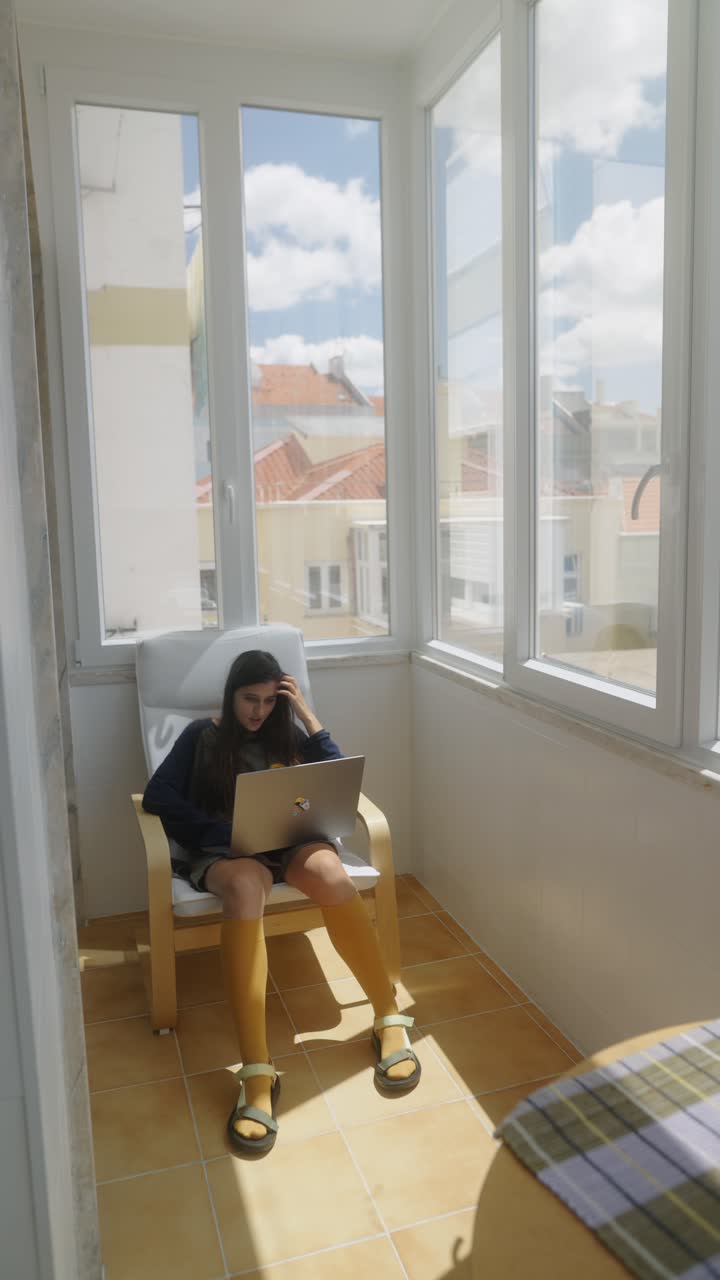 Young woman working on a laptop on a balcony