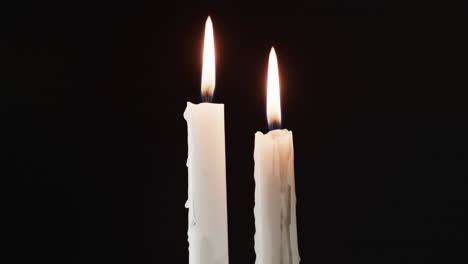 Video-of-two-white-candles-with-white-flame-and-copy-space-on-black-background