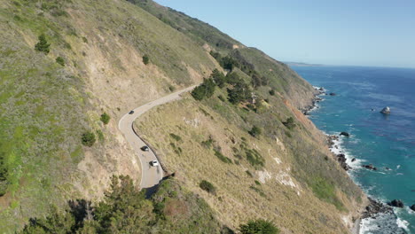 cars drive scenic coastal highway 1 in california overlooking ocean on sunny day