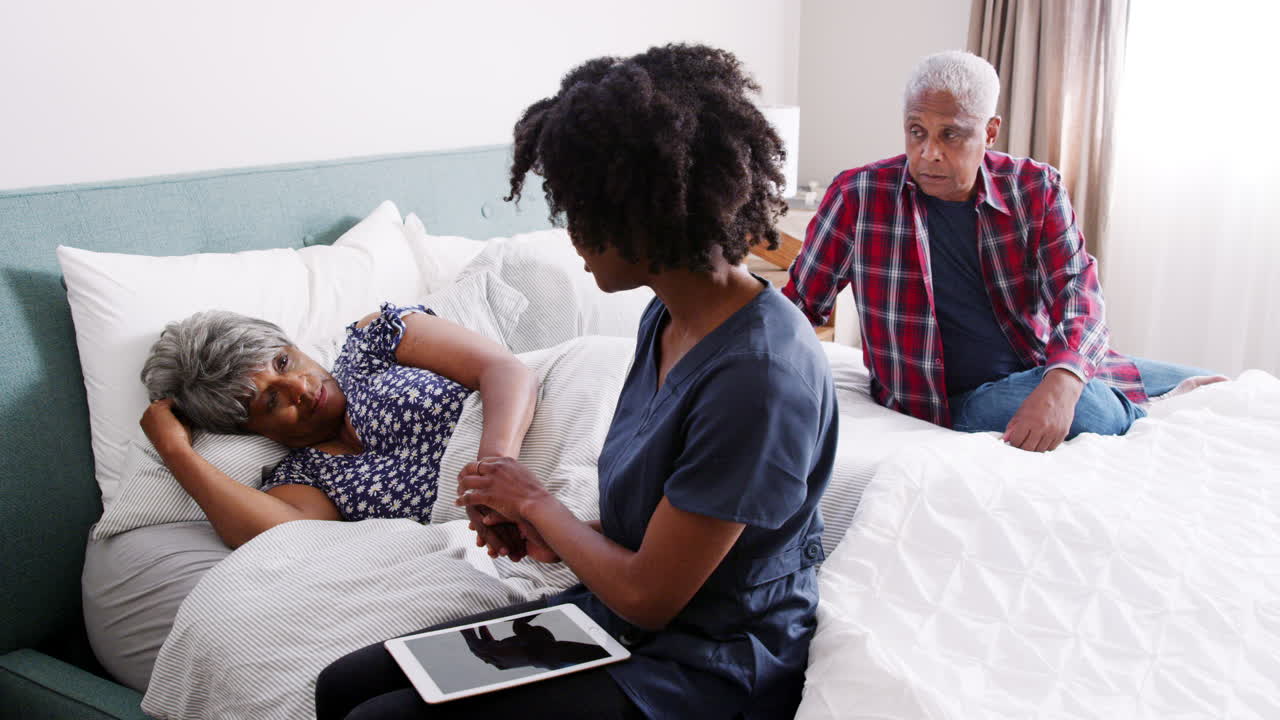 Nurse Visiting Senior Woman Lying In Bed Suffering With Depression