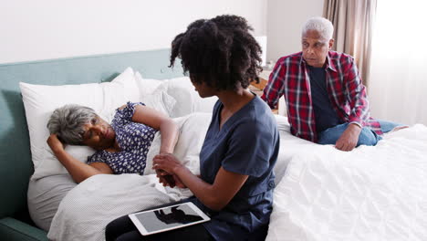 Nurse-Visiting-Senior-Woman-Lying-In-Bed-Suffering-With-Depression