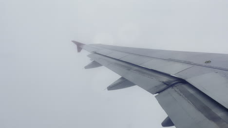 the wing of a flying airplane amidst dense clouds