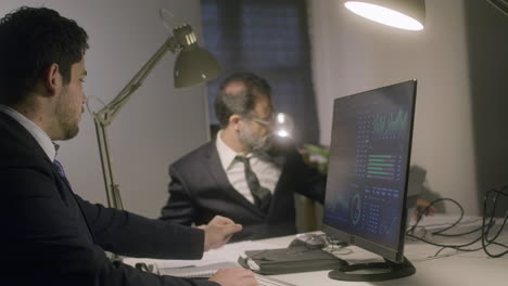 Two-male-colleagues-working-together-in-office-late