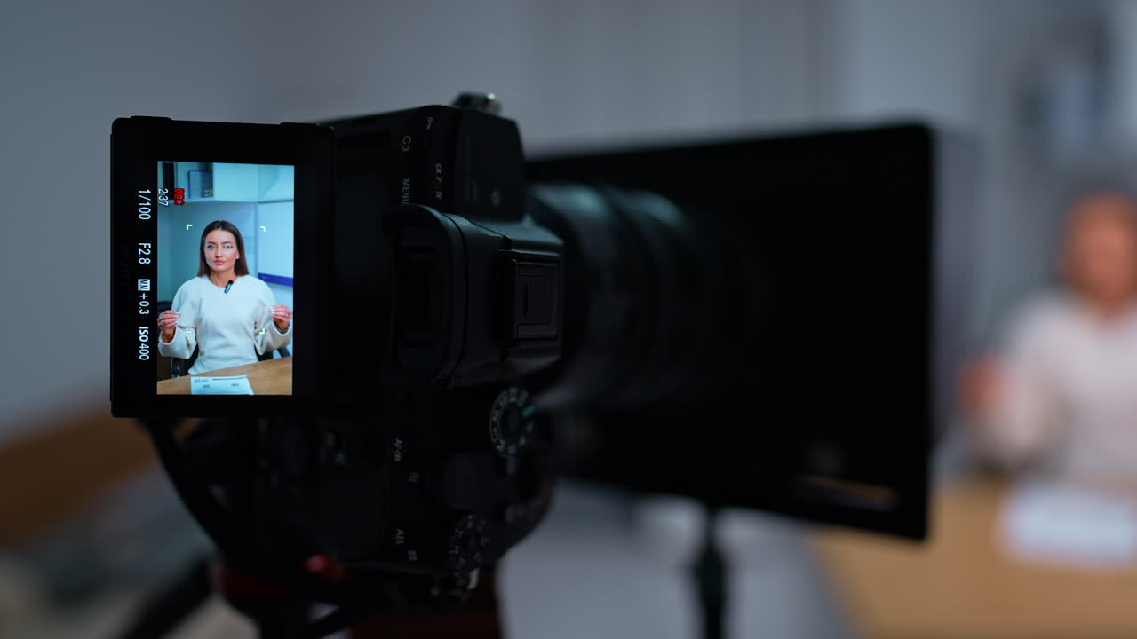 Switched on camera with display recording a woman. Creating blog concept in studio. Close up. Blurred backdrop.