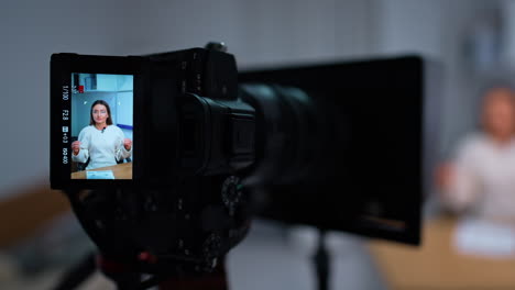 switched on camera with display recording a woman. creating blog concept in studio. close up. blurred backdrop.