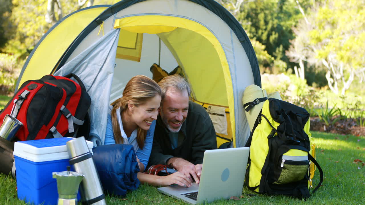 una pareja de excursionistas felices usando una computadora portátil