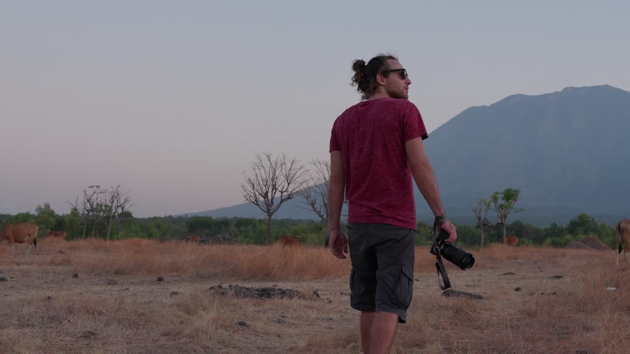 Young attractive man, rural location, mirrorless digital camera, slow-mo