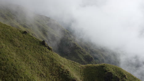 A-view-of-the-steep-alpine-pasture-in-the-Himalayan-Mountains-as-the-early-morning-fog-and-clouds-sweep-over-the-landscape-in-the-morning-light