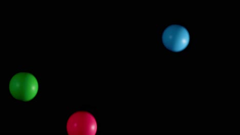 colorful balls in red, green, and blue bounce dynamically against a dark background.