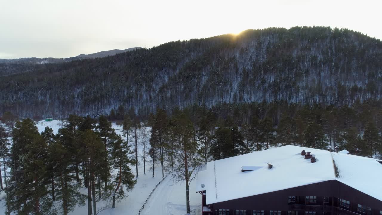 vista aérea de una cabaña en un bosque nevado con una montaña en el fondo