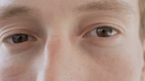 Close-up-shot-of-male-brown-eyes-looking-at-camera,-winking