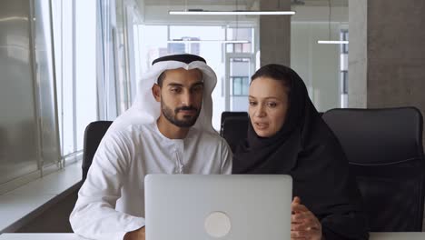 hombre y mujer guapos con ropa tradicional trabajando en una oficina de dubai