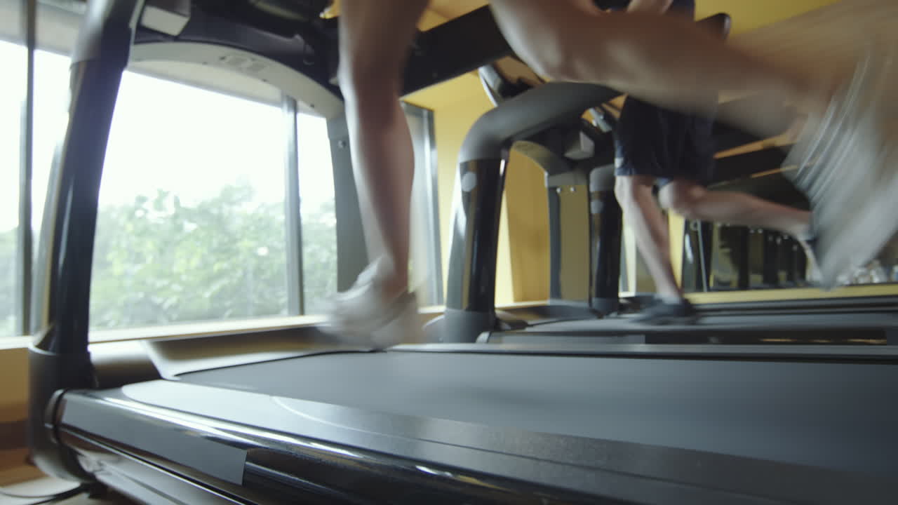 Man and Woman Running Fast on Gym Treadmills