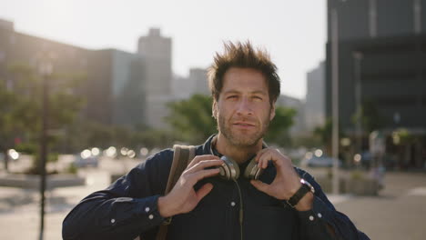 portrait of cool attractive caucasian man listening to music removes headphones looking   confident at camera in city