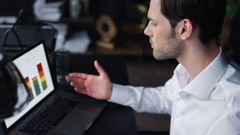 Businessman-looking-at-charts-on-laptop-in-office.-Employee-gesturing-hands