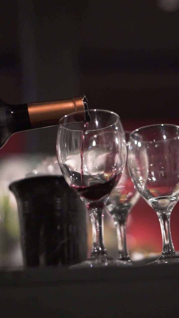 Una bottiglia versa vino rosso argentino tradizionale e famoso in un calice di cristallo durante un ricevimento serale.