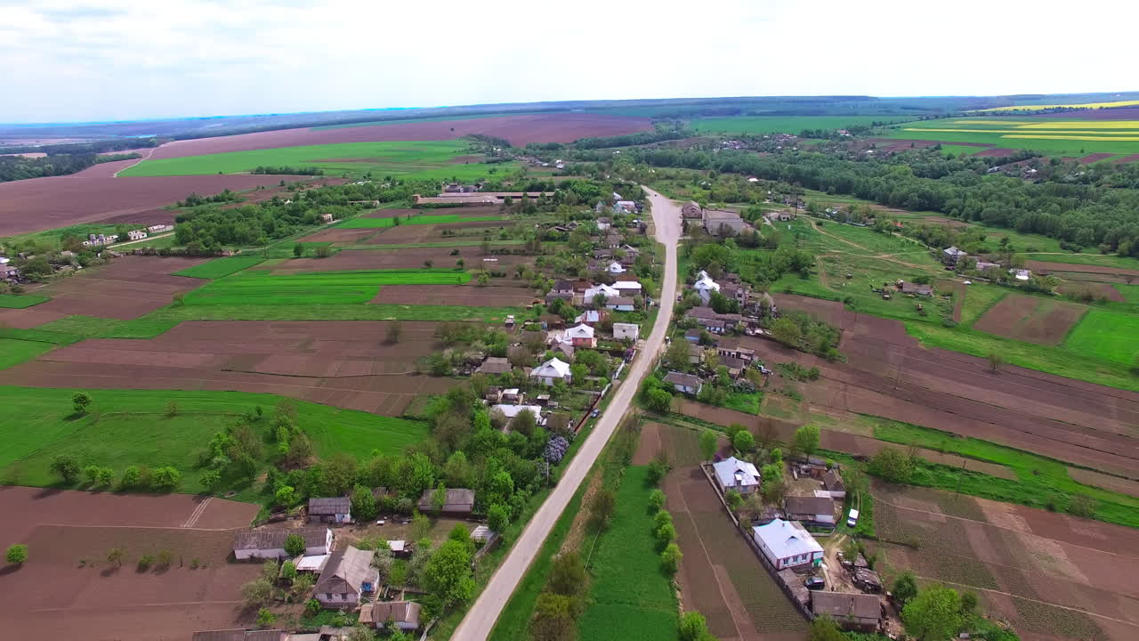 Road going through the village up to the farmlands. Lovely panorama of a rural countryside from aerial view.