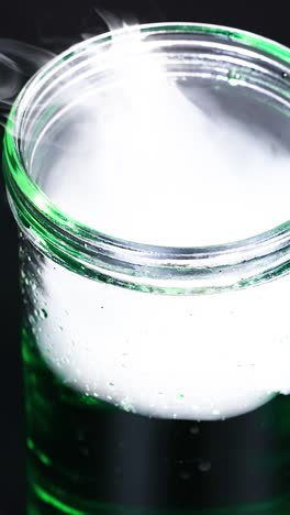 un vaso con hielo seco crea vapor nebuloso, mostrando una reacción química en un entorno controlado