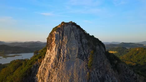 4k-Aerial-Pan-up-above-the-Buddha-Mountain-in-Pattaya-at-dawn,-golden-light-on-the-image-of-Buddha-in-Khao-Chi-Chan,-Chonburi,-Thailand