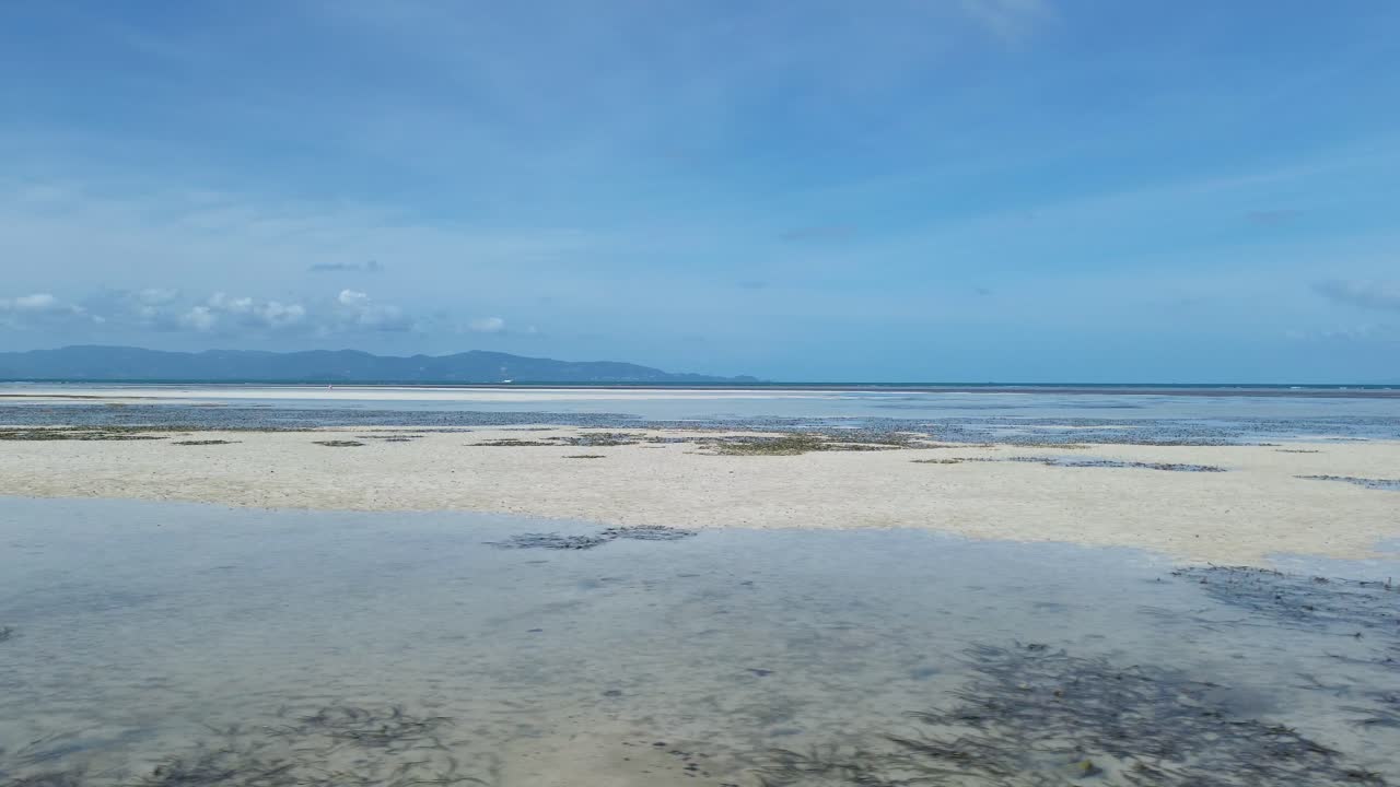 Aerial footage of Thong Sala Beach with a wide sandy shoreline, turquoise sea and lush tropical scenery on Koh Phangan island, Thailand