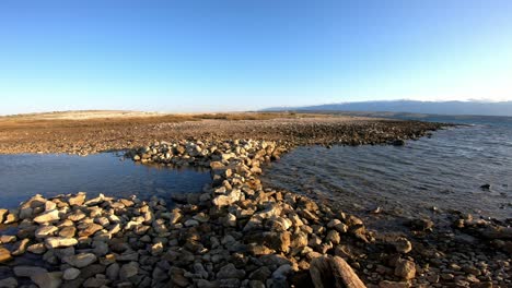 handheld camera walking over stony path towards water crossing made of piled up stones