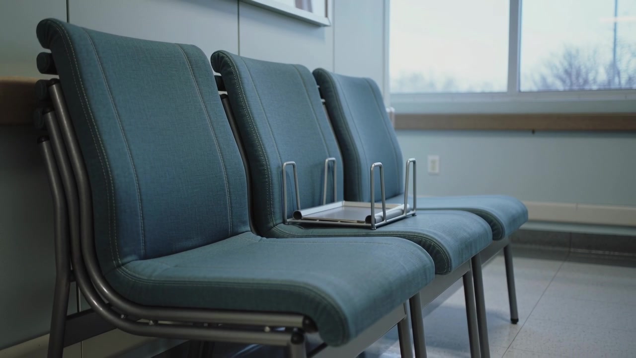 Flipping metal rack on center teal seat nudged unseen, tumbling from upright to inverted in clinic