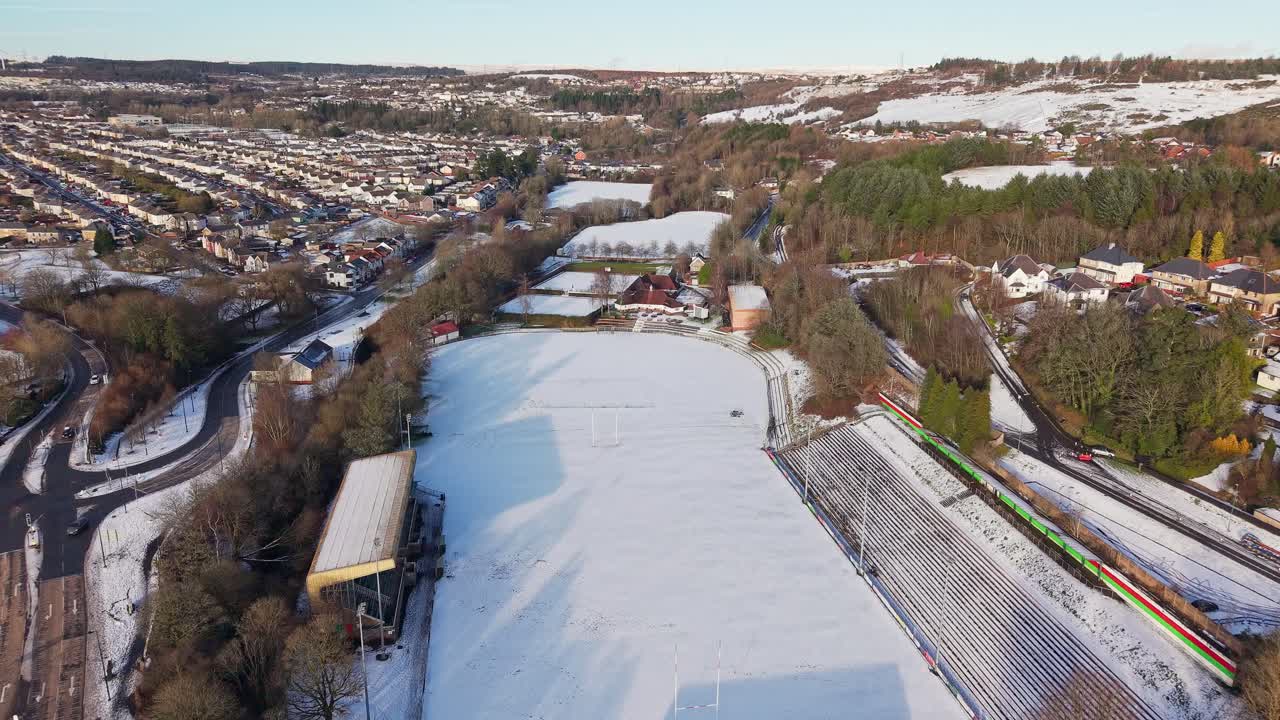 Drohnenaufnahmen, die auf einen schneebedeckten Rugbyplatz in Ebbw Vale, Wales, zufliegen