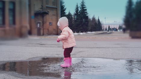 un niño pequeño está saltando en un charco dejando mucho spray