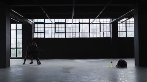 African-american-man-and-woman-standing-in-an-empty-building-playing-basketball